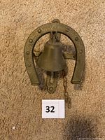 Front view showing horseshoe-shaped frame encasing metal bell with number marker.