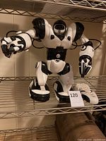 Front view of the Robo Sapien remote control robot showing black and white body and articulated limbs, along with its remote control.