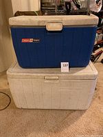Blue and white Coleman coolers stacked, showing front and label on blue cooler