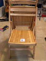 Front view of a folding wooden chair showing the slatted seat and backrest