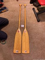 Two Upper Canada Paddle Company wooden paddles laid side by side on a carpet.