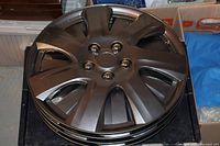 Stack of four black 17-inch hubcaps showing full top view with spokes design.