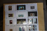 Photo showing multiple dealer cards with Russian stamps featuring portraits, animals, and historical themes on a wood surface.