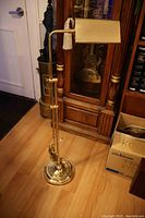 Full view of brass adjustable floor lamp showing base, vertical stem, adjustable arm, and rectangular shade.