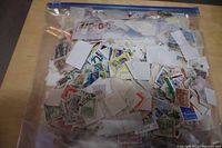 Full zip-top bag filled with a large quantity of used postage stamps, mostly loose and in various colors and sizes.