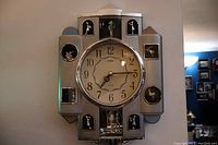 Full view of the VStride musical wall clock showing central round clock face and multiple musician figurines surrounding it in silver-tone metal frame.