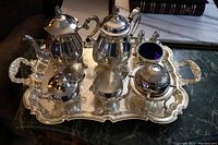 Full set on tray including tea pot, coffee pot, creamer, sugar bowl, waste cup, butter dish, salt and pepper shakers, and tongs.