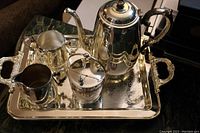 Full view of entire silver plated tea set on tray showing teapot, sugar bowl, creamer, waste cup, and tray handles and engraving.