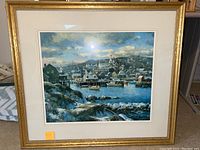 Framed print showing full scenic port town with buildings, boats, and water.