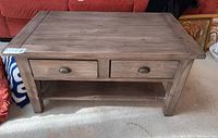 Front view of rustic reclaimed wood coffee table showing two drawers with metal cup handles and lower shelf.