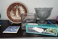 Photo showing the collector's plate, Towle silver plated towel box, clear cube glass vase, and cut glass serving bowl on a surface.