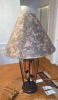 Front view of leaf design metal table lamp with fabric shade on wooden table.