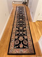 Full length of black floral Safavieh runner rug on hardwood floor.