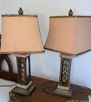 Front view showing two matching table lamps with metal and stone bases and rectangular beige fabric shades.