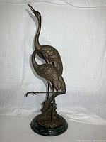 Full frontal view of dual brass cranes on green marble base