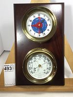 Front view of brass tide clock and barometer mounted on wood plaque
