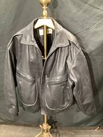 Front view of black men's leather jacket made from deerskin, showing collar, zipper closure and two front patch pockets.