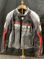 Front view of black leather motorcycle jacket with Ducati Performance branding and red and white stripes