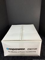 White cardboard retail box labeled “Empower EM2100 The Mastery of Power Conditioning.”