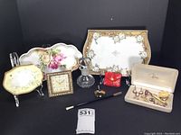 Group photo of all items including ceramic trays, perfume bottle, jewelry box, clock, pen, and smoking accessories
