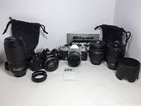 All items arranged front view: two SLR bodies with lenses, three zoom lenses, hoods, flash, filter, adapter ring and bags