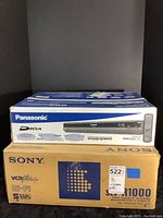 Stacked Panasonic and Sony boxes against black background
