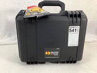 Closed black Pelican iM2100 camera case with tags visible and carrying handle on top.