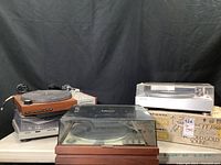 Overview of five turntables stacked and arranged: Marantz 6300, Technics SLD3, Garrard Zero 100, Harman Kardon ST7 and Marantz TT1060 in box