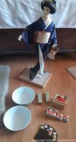 Geisha doll, two bowls, stone stamps and miniature figurines spaced on the floor