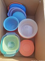 Box with assorted Tupperware containers of various shapes and colors stacked inside.