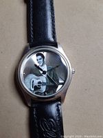Close-up front view of watch face showing Elvis Presley image and guitar, clear watch hands visible.