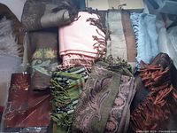 Lot of scarves showing a variety of colors and patterns with fringe edges, laid out to display all items.