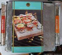 Full view of Himalayan pink salt plate with packaging and two spice blends on each side, against a grill background