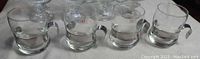 Set of four clear glass hot drink glasses with silver plated handles.