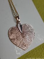 Heart-shaped gold filled leaf pendant with visible vein detail and small attached gold leaf on thin gold chain necklace
