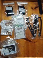 Jewelry collection displayed on wooden surface including hoop earrings, bracelets, and black lace accessories in plastic packaging.