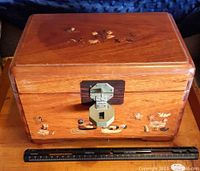 Closed wooden box showing embossed duck and water scene motifs on the front and top with a metal latch.