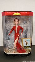 Full boxed view of Marilyn Monroe Barbie from Hollywood Legends Collection showing doll in red gown, box with movie poster background and collector edition label.