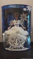 Front view of the Cinderella Holiday Princess doll in original blue packaging with snowflake decorations and Walt Disney Cinderella branding.