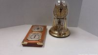 Barometer on wooden plaque with gold corners and gold coloured clock adjacent