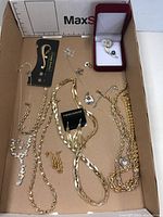 Overview image of lot showing multiple gold-tone chain necklaces, bracelets, earring pairs, and a boxed floral brooch.