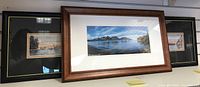 Two framed art prints displayed side by side, one with a brown frame and blue water-themed panoramic print and another with a black frame and matching side prints.