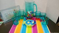 Jug, multiple cups, decorative dish and serving tray on colorful striped background