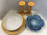 Photo showing blue ceramic serving bowls, yellow ceramic bowl, large yellow serving tray and pair of yellow wooden candlesticks.