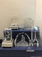 Five Swarovski crystal collectibles arranged including dolphin figures in crystal blocks, Eiffel Tower, The Little Mermaid sculpture, and a crystal block with a floral or abstract design.