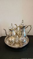 Full silver plate tea set including cream, sugar, tea pot, and water pot displayed on tray