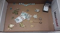 Overview of multiple pieces of costume jewelry spread in a box, including earrings and a bracelet