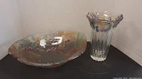 Wide view showing both the large shallow decorated glass bowl and the tall decorated glass vase side by side.