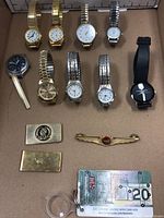Full lot of wrist watches and tie clips arranged in cardboard box, showing diversity in styles and accessories.