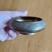 Side angle showing engraved floral etching on brass bowl and flared shape